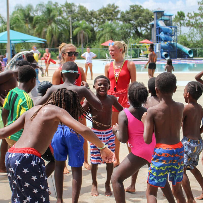 Elementary students celebrate the end of GYAC's summer camp by dancing with lifeguards during their pool party.